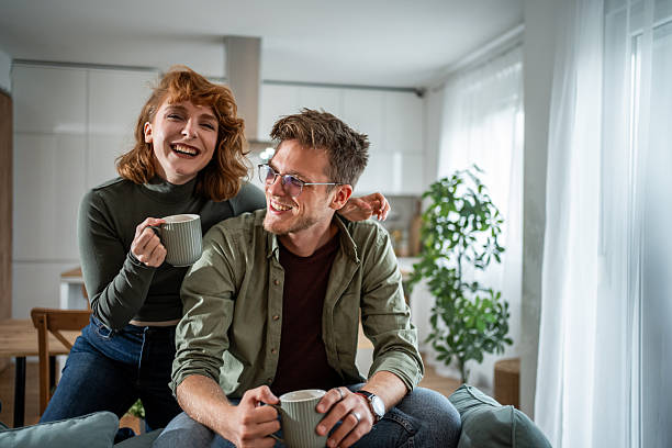 istock Cheerful couple laughing and drinking coffee on sofa at home 2216339848