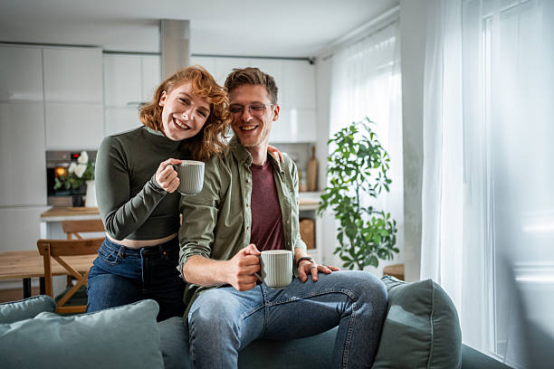 istock Young couple smiling and drinking coffee on sofa in living room 2216339855