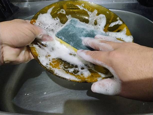 istock Hand with a sponge washing a plate. 2216342690