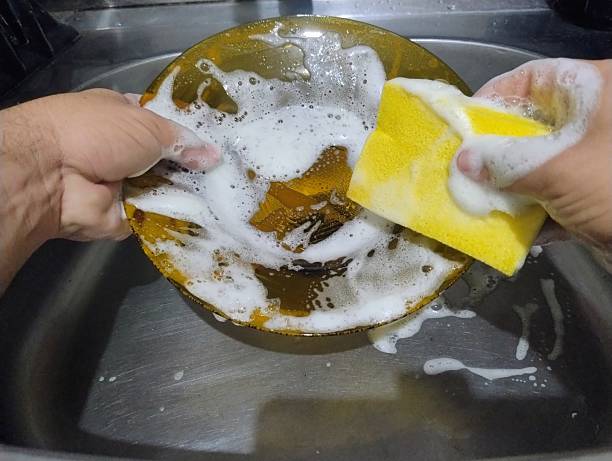 istock Hand with a sponge washing a plate. 2216342694