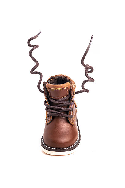 One Brown Children's boot made of leather for a boy on a white background with developing laces. Close-up.