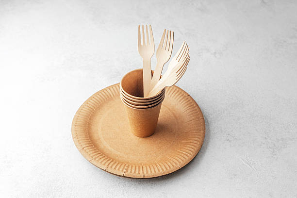 istock Eco paper cups with wooden forks on disposable plate on white background 2216353733