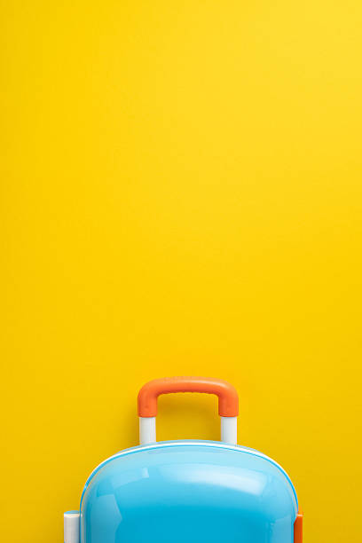 istock A blue and orange vertical suitcase placed against a vibrant yellow background symbolizing travel 2216361793