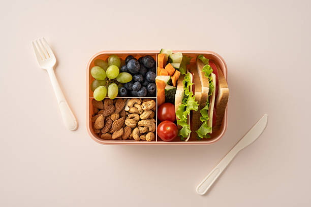 istock Packed lunch featuring sandwiches, fruits, nuts, and vegetables displayed in a divided container 2216361795