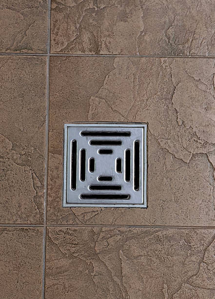 istock drain cover set in textured brown tile floor in modern interior setting. closeup. 2216365274