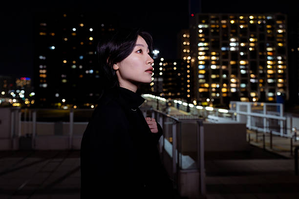 istock Young woman looking at cityscape at night 2216368128