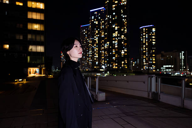 istock Young woman looking at cityscape at night 2216368166