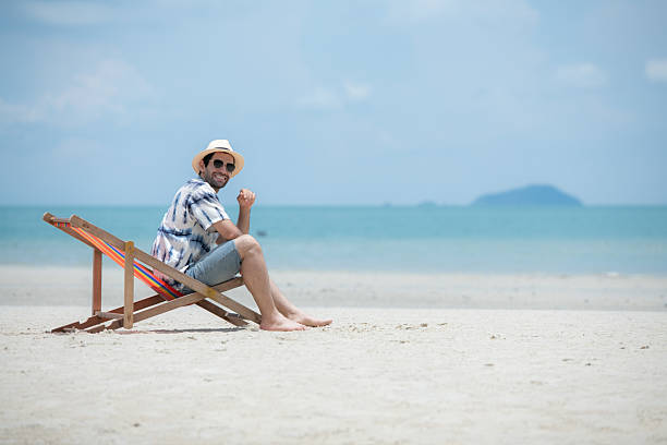 istock Young man on vacation on a white sandy beach, clear sky and sea 2216368185