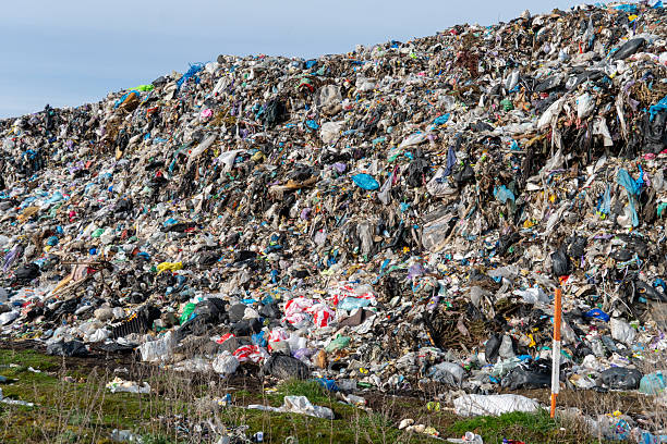 istock Extensive Landfill Area Filled with Mixed Waste Materials and Green Grass Environment 2216370853