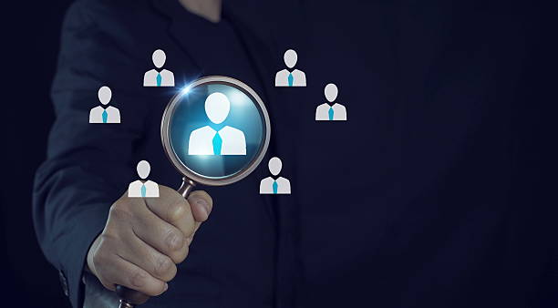 istock HR, Human Resources Selection and Recruitment Concept. HR professional holding magnifying glass focusing on candidate icon, symbolizing employee selection, recruitment. 2216373964