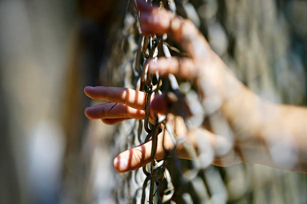 istock Hand Reaching Through Chain Link Fence in Natural Background 2216374768