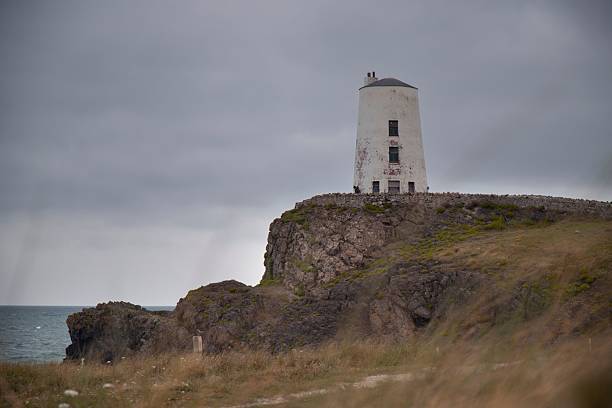 The Twr Mawr Lighthouse stands on a rocky cliff in Anglesey, Wales.