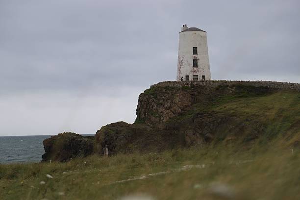 The Twr Mawr Lighthouse stands on a rocky cliff in Anglesey, Wales.