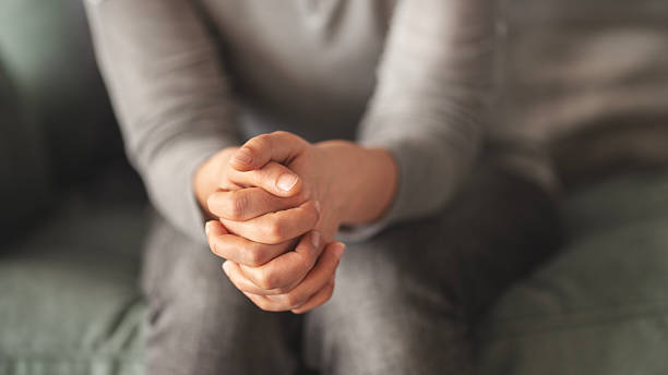 istock Close up young woman sitting on sofa with folded hands on knee 2216381664
