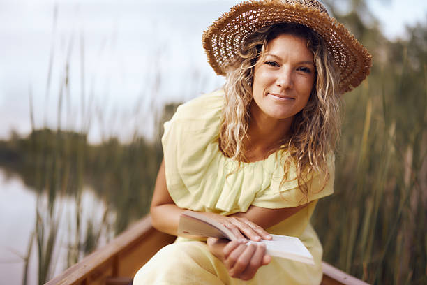 istock Smiling woman enjoying in book during spring day in a canoe. 2216384973