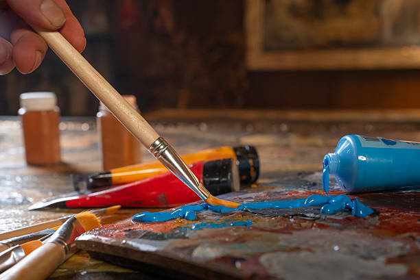 istock Artist s hands with brushes mixing colors 2216391051