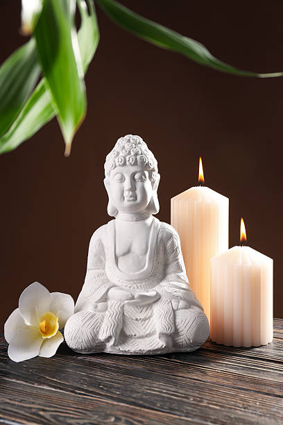 istock Buddha statue, flower, candles and bamboo on brown background 2216391167