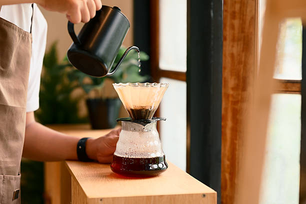 istock Close up of man brewing coffee with pour over method using a glass dripper in a kitchen 2216393431