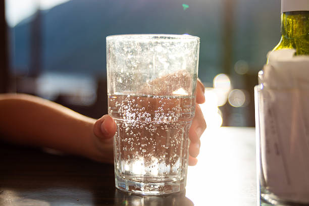 istock A child's hand holds a glass with sparkling water on the table 2216394687