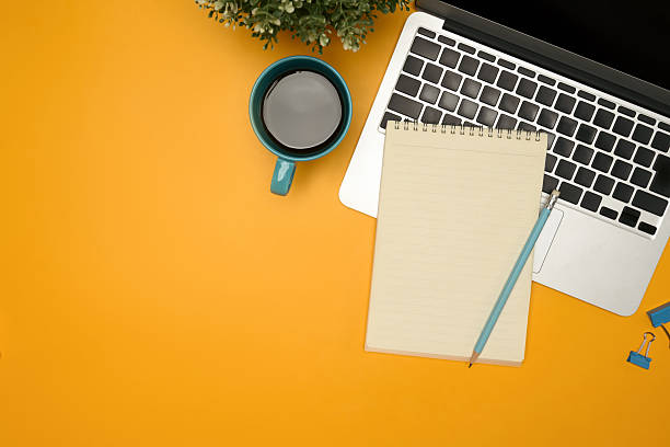 istock Flat lay of modern desk with a coffee cup, laptop and notebook on yellow background 2216394792
