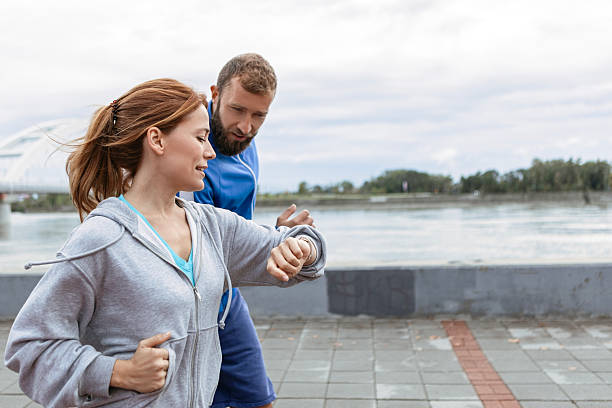 istock Happy Couple Jogging Outdoors and Checking Fitness Tracker 2216395519