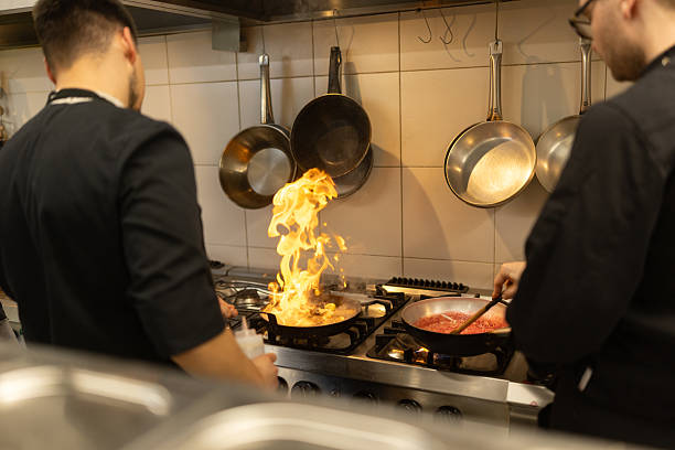 istock Chef and sous-chef cooking with fire in commercial kitchen 2216396604