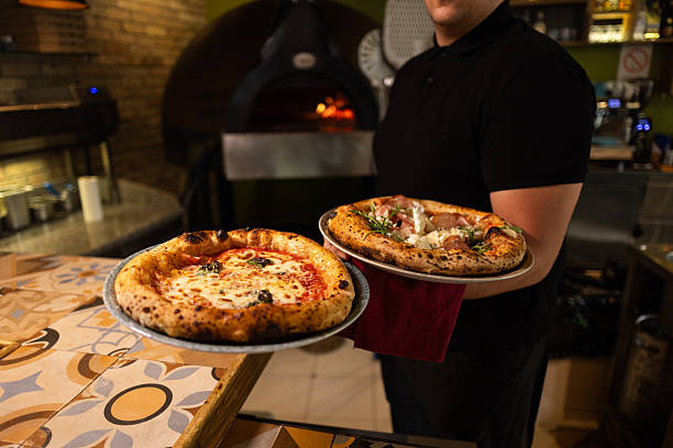 istock Chef holding two freshly baked pizzas while working in restaurant kitchen 2216396736