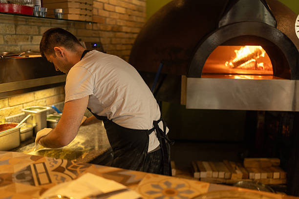 istock Man kneading pizza dough while working in pizzeria 2216396819