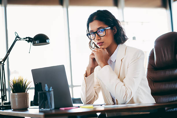 istock Charming businesswoman working thoughtfully in a modern office interior setting with a laptop and professional attire 2216397312