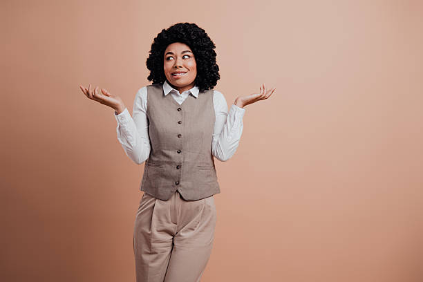 istock Confident young professional woman with hands raised in gesture expressing uncertainty against beige background 2216397697