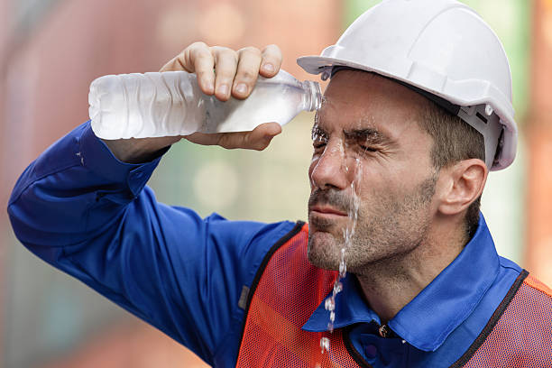 istock Man in hard hat pouring water on his face to refresh, Construction worker suffering from heat, Worker cooling off with water on a hot day, seeking relief 2216398399