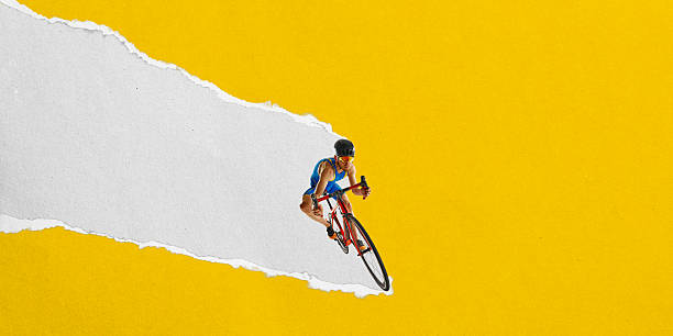 Male cyclist rides on diagonal torn paper stripe against yellow background. Textured scrap collage. Dynamic graphic design. Athlete tearing through background. Concept of sport, race, endurance, speed