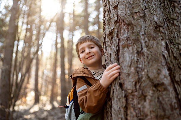 istock Little boy hugs a tree while posing for a portrait in the forest 2216398763