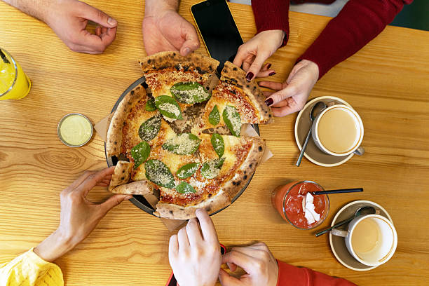 Friends sharing pizza, coffee, and juice at a restaurant table