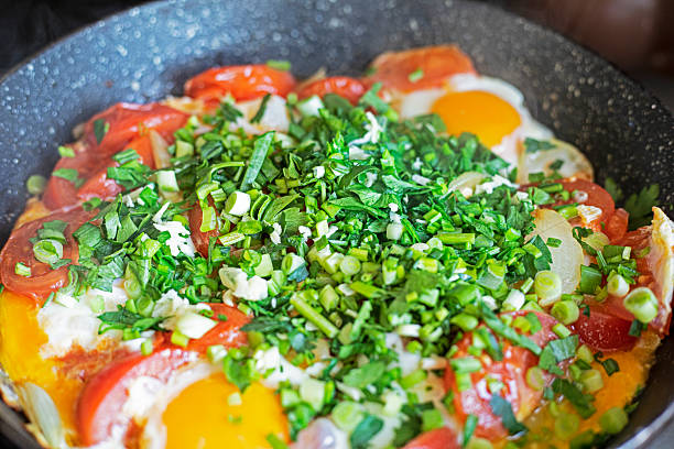 cooking scrambled eggs with tomatoes and green onions