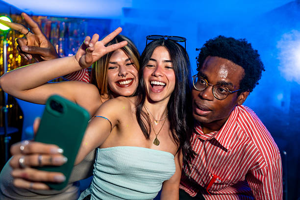 istock Friends taking a selfie at a lively party, gesturing peace signs 2216403573