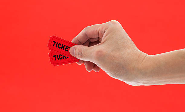 istock Hand holding two cinema tickets on red background 2216406130