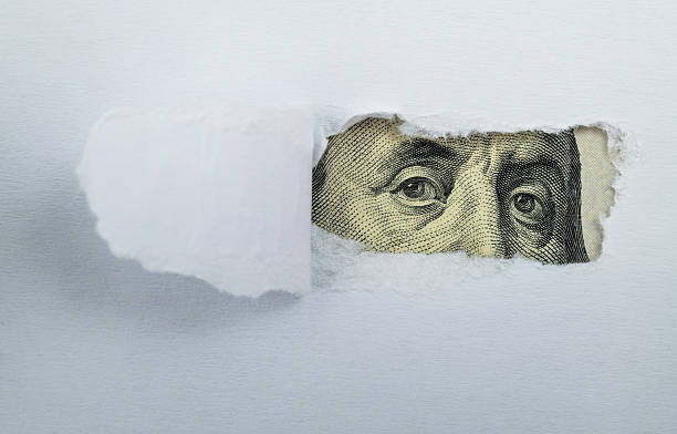 Torn white paper revealing US Currency