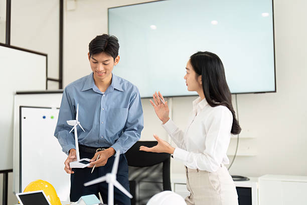 istock Sustainable Engineering and Innovation. Engineers discussing renewable energy solutions with wind turbine models in a modern workspace. 2216406677