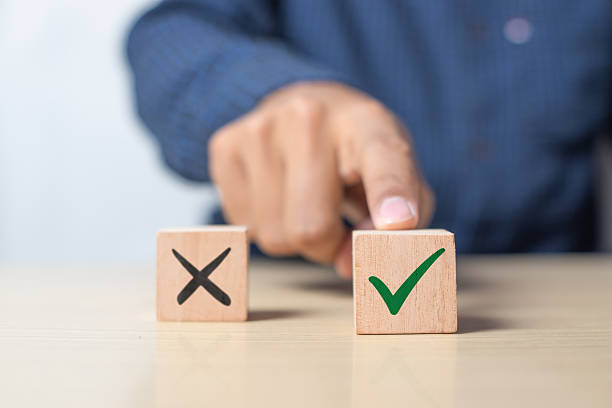 istock A man choosing between a checkmark and an 'X' symbol on wooden blocks. The image represents the concept of making the right choice, emphasizing the importance of distinguishing between right and wrong 2216408209