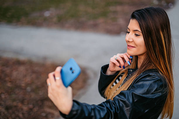 istock Young Woman Taking Selfies Using Phone In The City 2216409632
