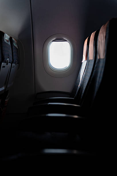 Soft sunlight streaming through airplane window, casting gentle glow across vacant passenger seats with peaceful, tranquil ambiance