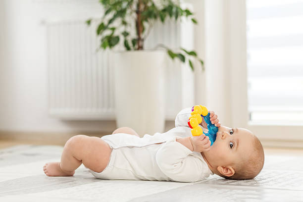 istock Baby plays with colorful toy in a bright indoor setting on a soft surface. Copy space 2216418098