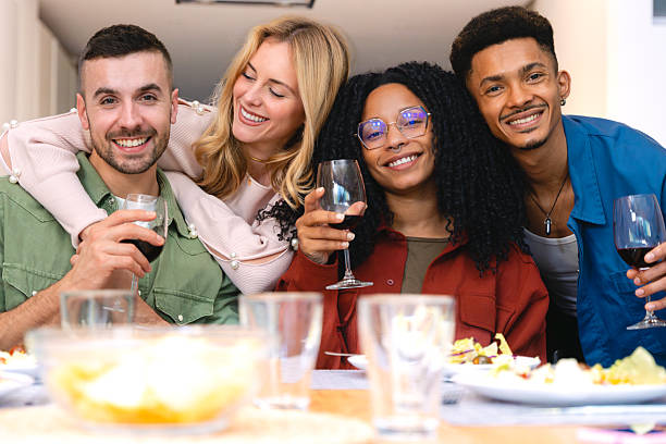 istock Smiling multiethnic friends enjoying dinner and wine together at home table 2216426073