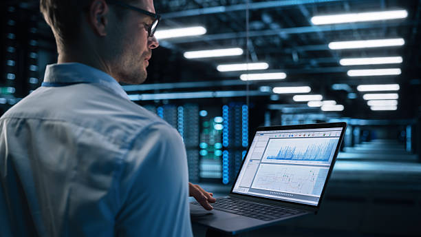 istock View Over the Shoulder of Male IT Specialist Using Laptop Computer in Data Center, Looking at the Screen. Successful Businessman and e-Business Entrepreneur Working Alone. Innovation Concept 2216426267