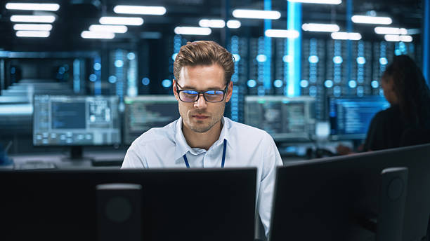 fokussierter systemadministrator oder berater schaut auf den bildschirm und speichert backup-daten in dark evening room workplace station indoors. konzept der netzwerktechnologien - datenschutz stock-fotos und bilder