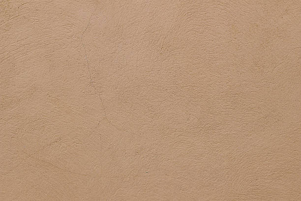 istock Old rough beige ochre colored cracked painted plaster wall texture. Earth coloured grunge texture, building facade. Closeup of historical house detail. Faded neutral backdrop, empty copy space. 2216428780