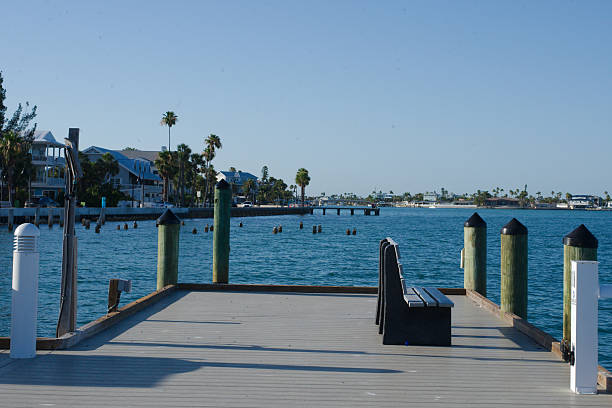 A serene waterfront scene from Merry Pier featuring boats docked in a calm harbor, with nearby greenery and palm trees under a clear sky, showcasing a peaceful coastal atmosphere ideal for relaxation and waterfront activities.