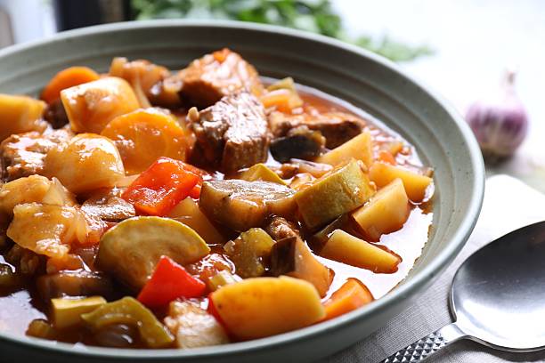 istock Delicious stew with vegetables in bowl and spoon on table, closeup 2216467914
