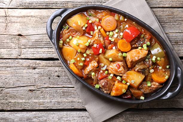 istock Delicious stew with vegetables in baking dish on wooden table, top view. Space for text 2216468408